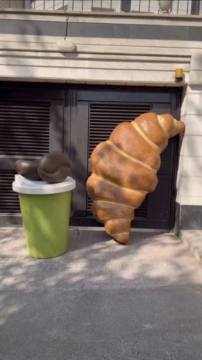 Giant croissant and coffee cup sculptures outside a café