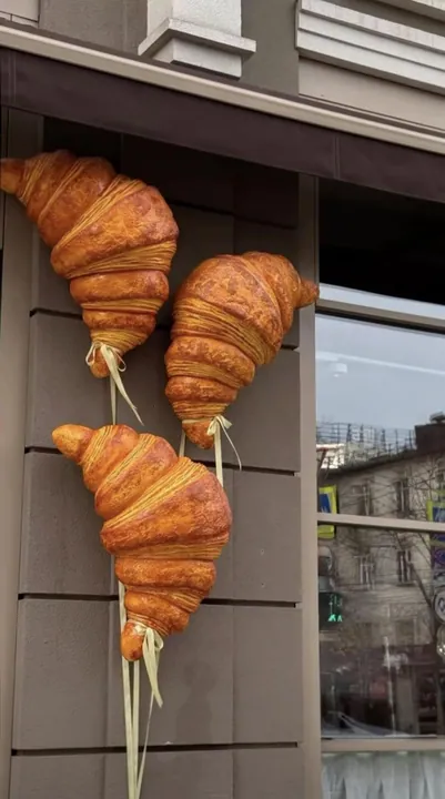 Oversized croissant sculptures mounted on a bakery storefront