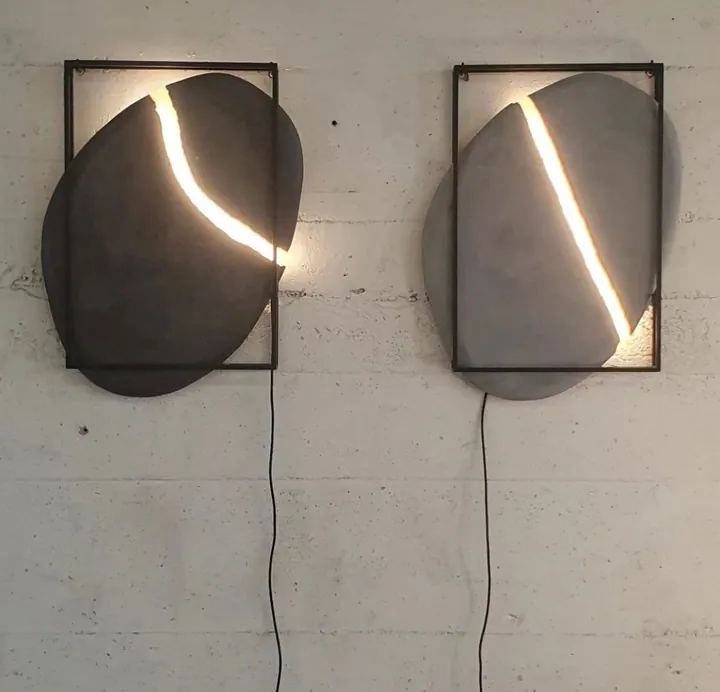 Pair of dark pebble-shaped sconces with a glowing seam of light